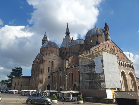 Eine große Kirche in Padua mit drei Kuppeln und spitzen runden Türmen dazwischen. 