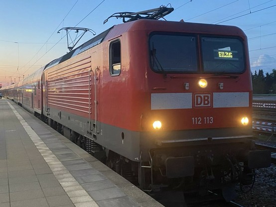Roter RE Triebwagen steht vor einem dämmerndem Himmel am Bahnsteig. Im Fenster ist eine LED Schild mit der Aufschrift 